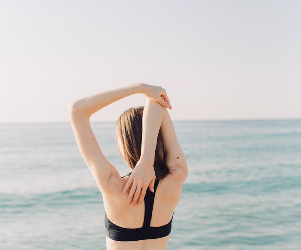 Person feeling energized and stretching outdoors with the sun shining.